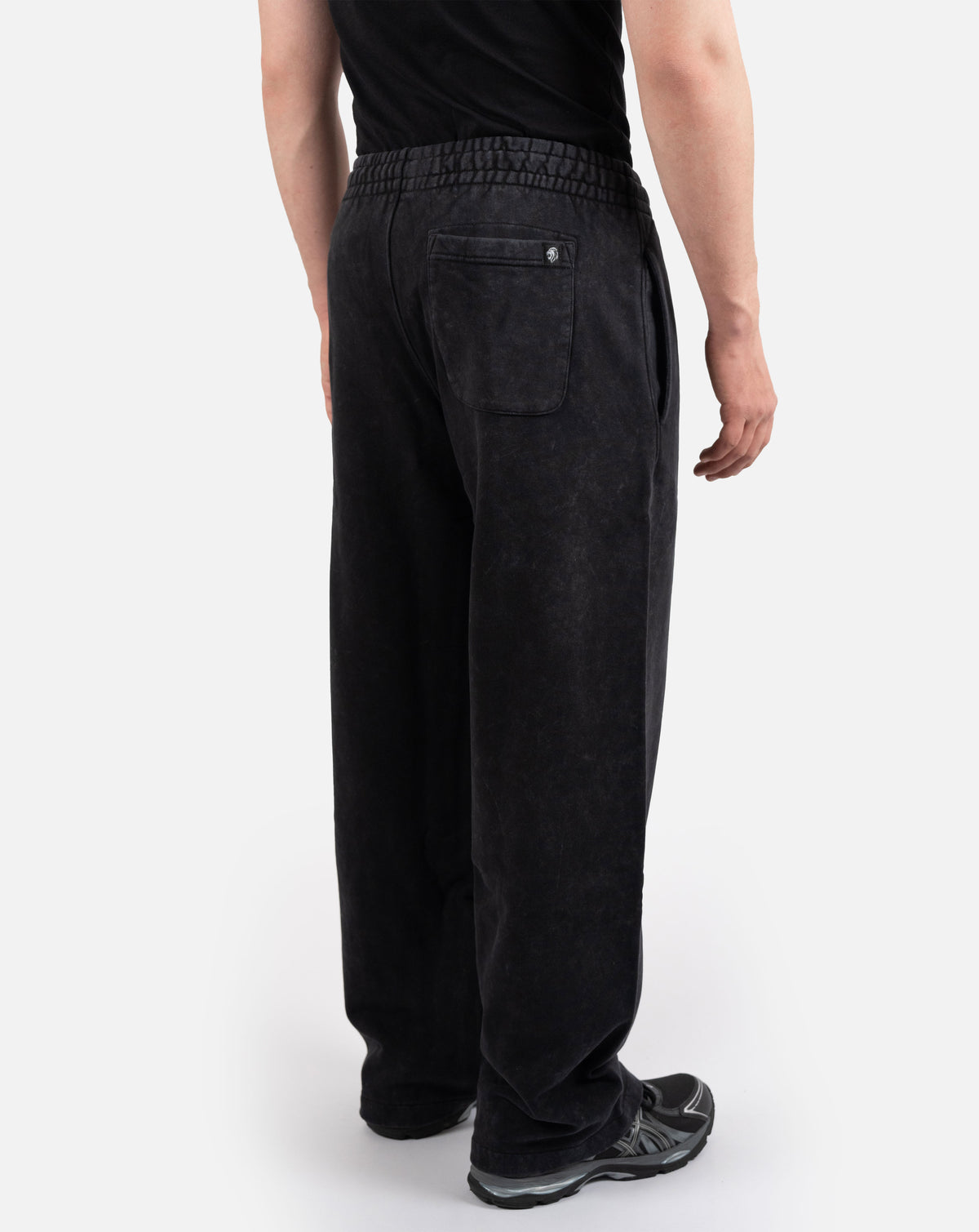 BEASTHAMMER Embrace Discipline baggy joggers in washed black, worn side view showing the wide straight leg