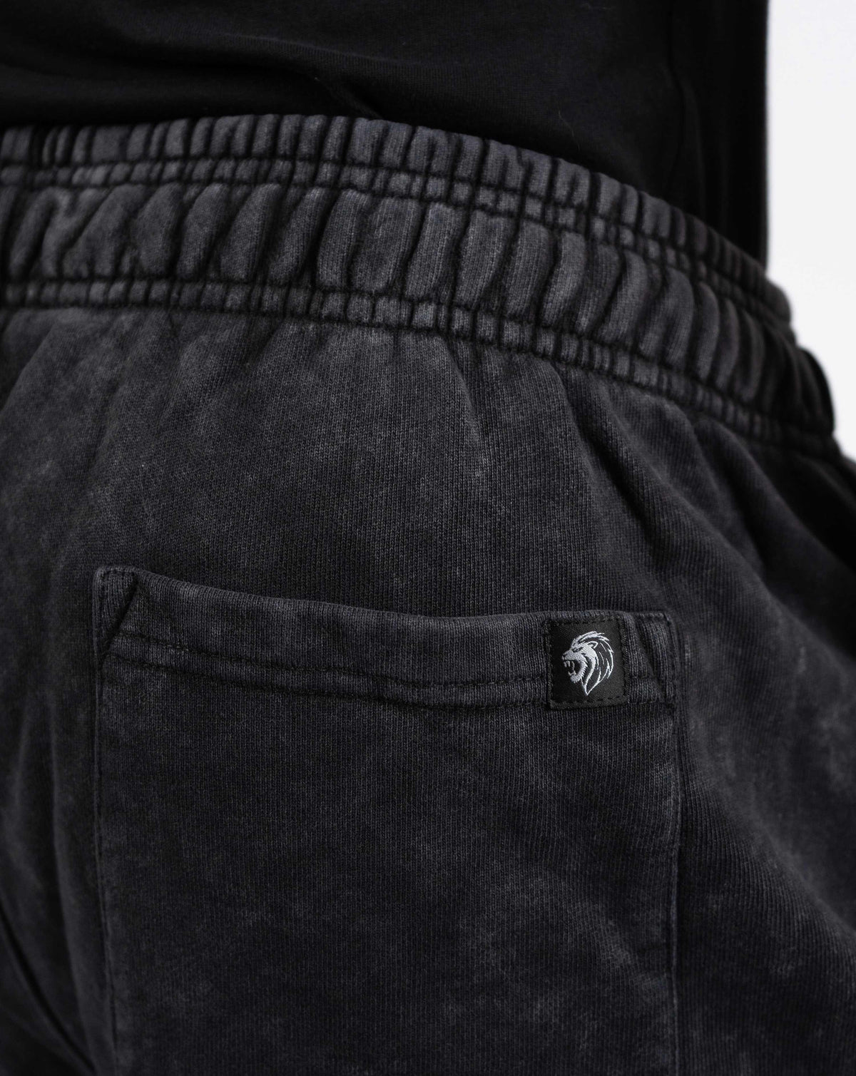 BEASTHAMMER Embrace Discipline cuffed joggers in washed black, close-up of the back pocket and logo badge