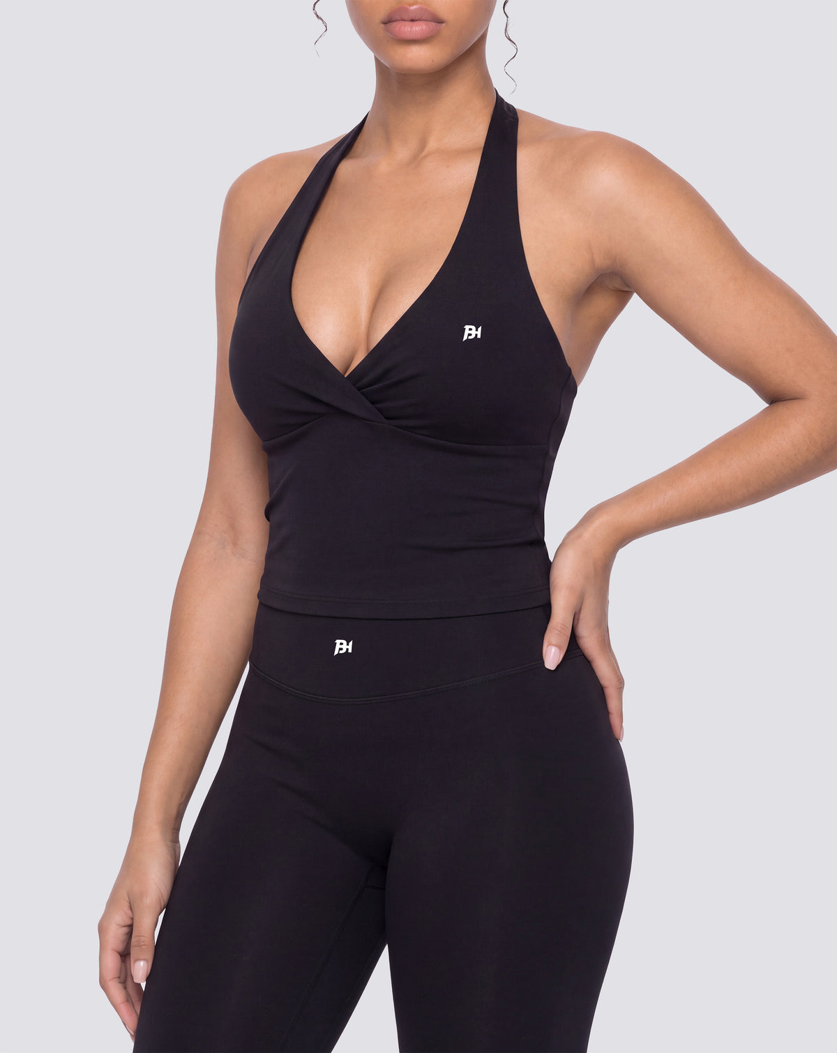 BEASTHAMMER Signature halter top in black, worn front view with halter neck and ruched twist, styled with matching Signature scrunch leggings
