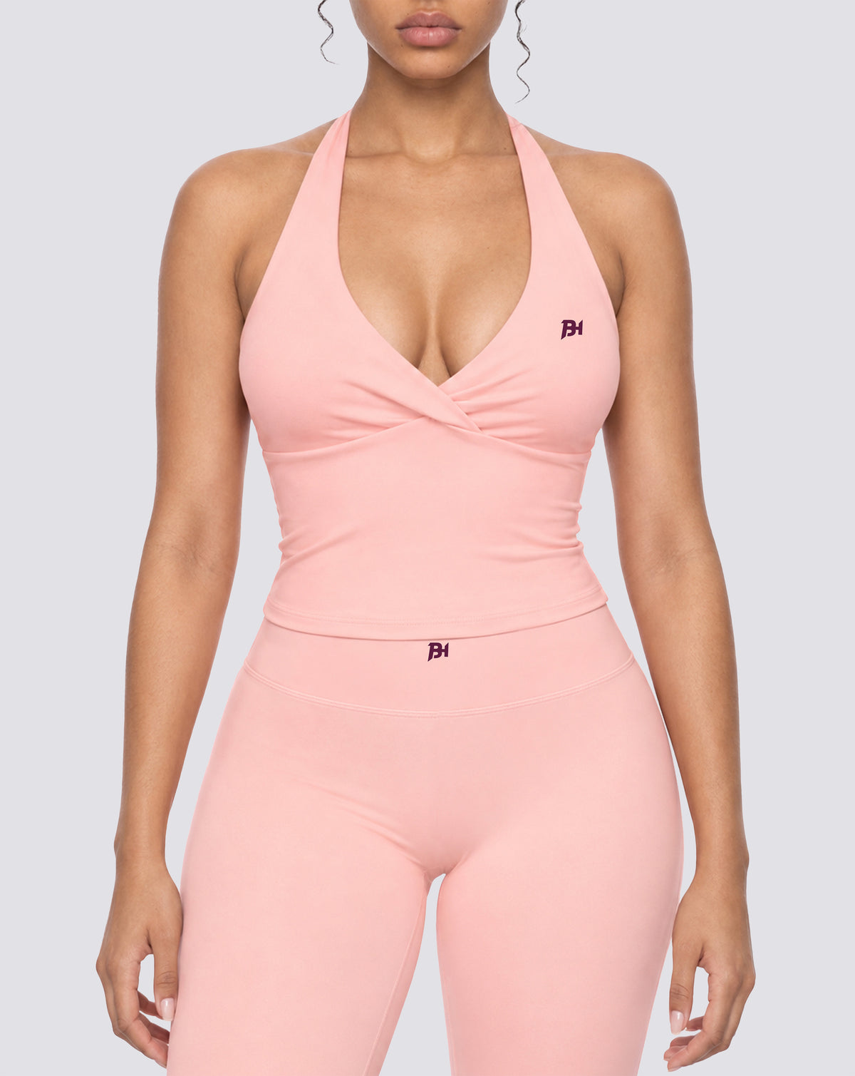 BEASTHAMMER Signature halter top in pink, worn front view with ruched twist front and BH monogram, styled with matching Signature scrunch leggings
