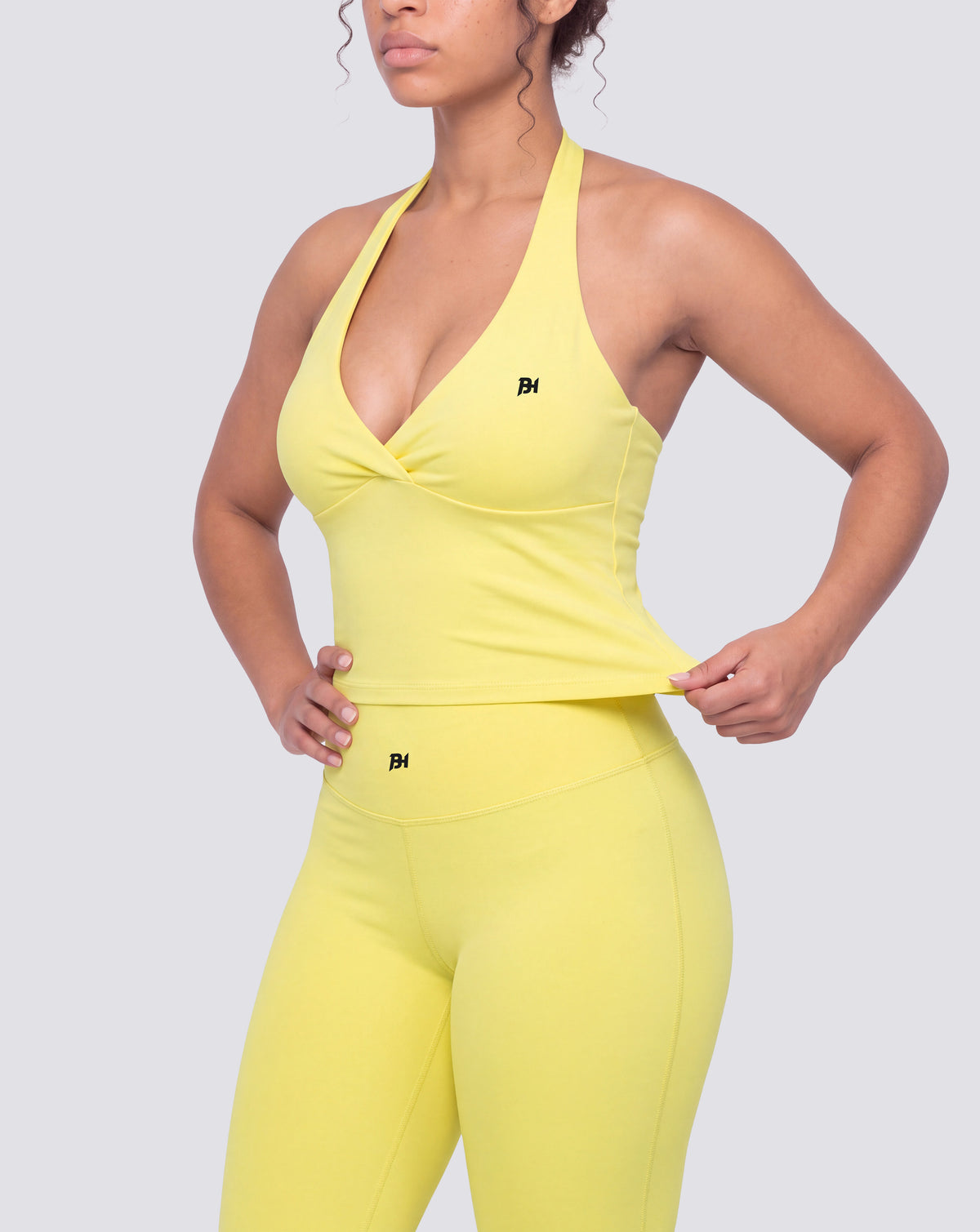 BEASTHAMMER Signature halter top in butter yellow, worn front three-quarter view showing the halter neck and cropped length