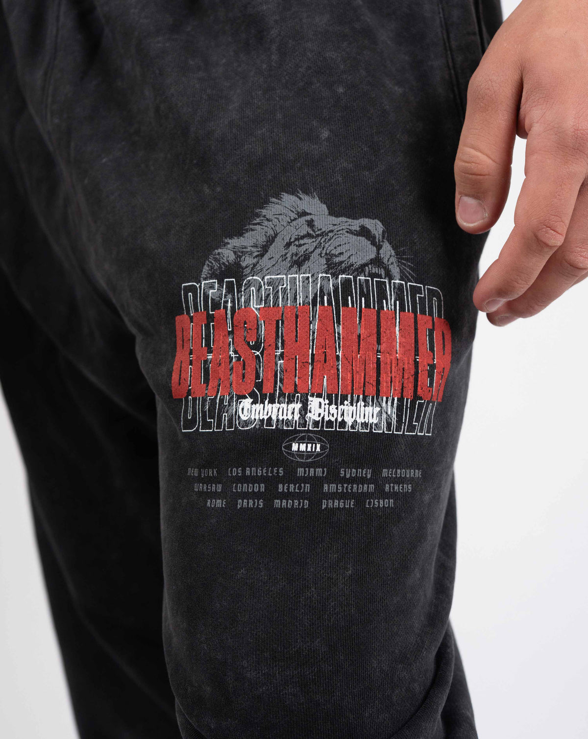 BEASTHAMMER Embrace Discipline cuffed joggers in washed black, close-up of the red BEASTHAMMER thigh print