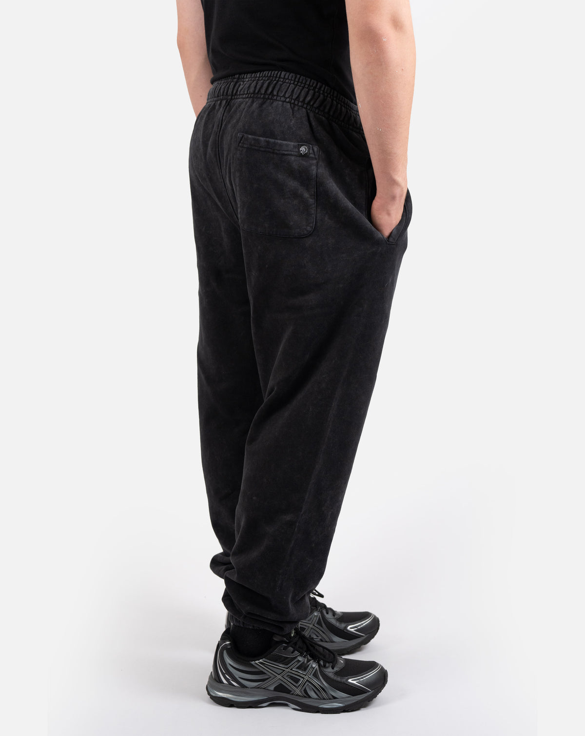 BEASTHAMMER Embrace Discipline cuffed joggers in washed black, worn side view showing the tapered leg and cuffs