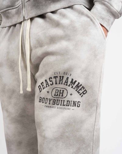 BEASTHAMMER Formed by Discipline baggy joggers in faded grey, close-up of the BEASTHAMMER BODYBUILDING thigh print