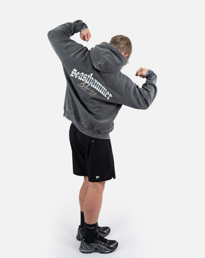 BEASTHAMMER Snow Wash oversized hoodie in washed black, worn back view with arms flexed
