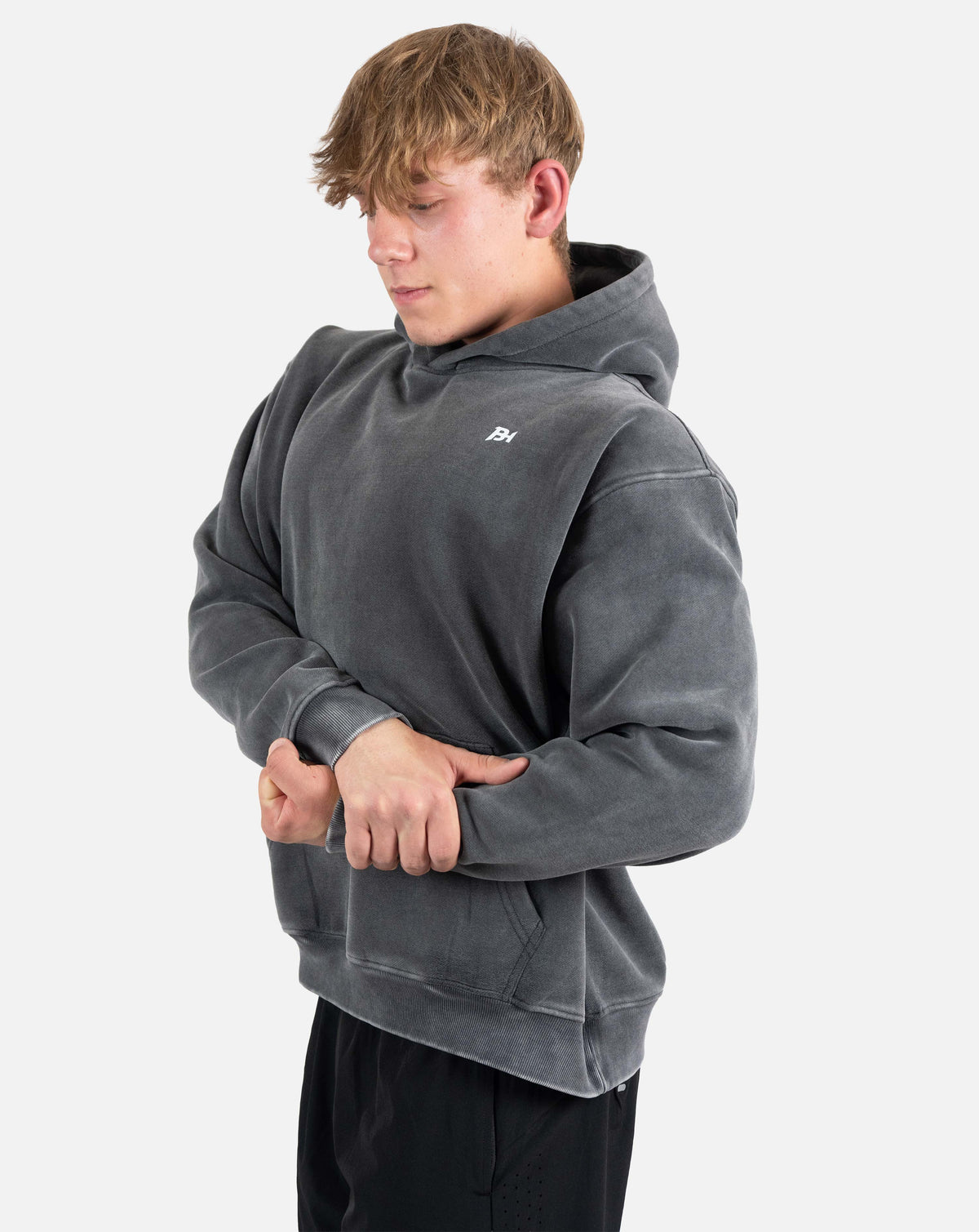 BEASTHAMMER Snow Wash oversized hoodie in washed black, worn three-quarter front view with the small chest logo