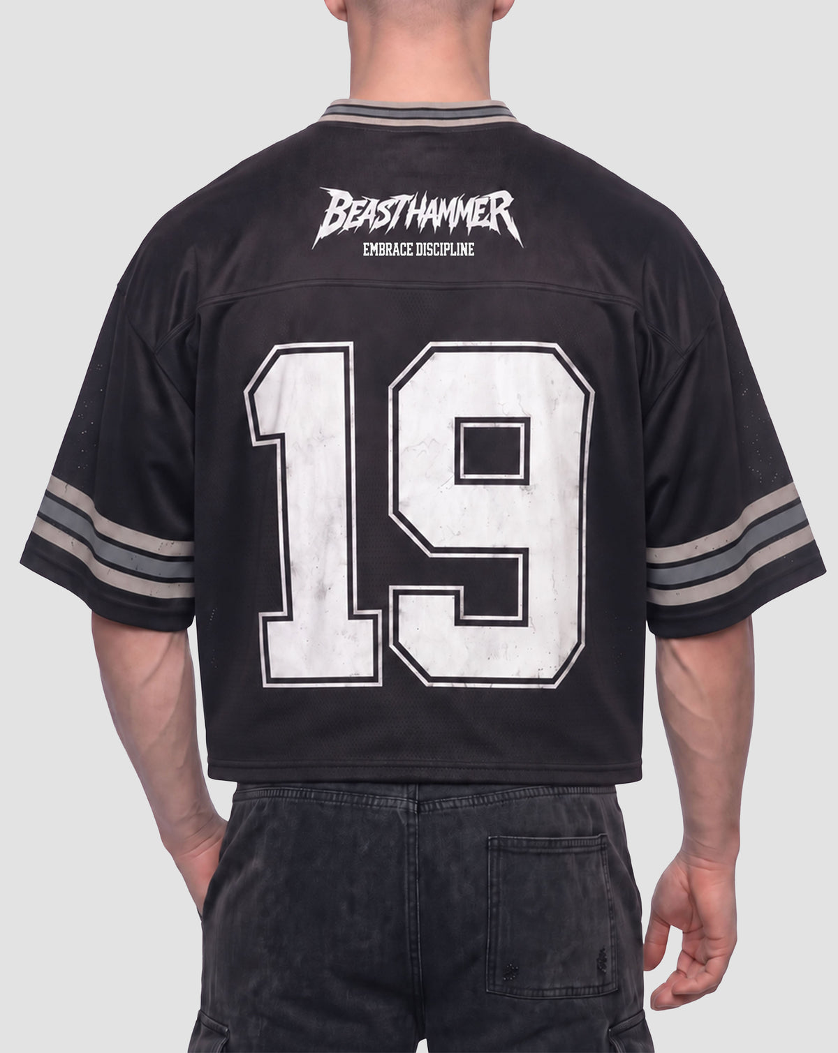Man wearing the BEASTHAMMER Varsity 19 Jersey in black, back view with BEASTHAMMER logo, EMBRACE DISCIPLINE and a large distressed white 19
