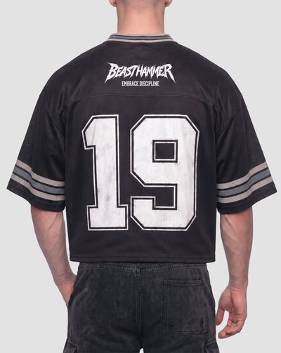 Man wearing the BEASTHAMMER Varsity 19 Jersey in black, back view with BEASTHAMMER logo, EMBRACE DISCIPLINE and a large distressed white 19