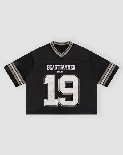 BEASTHAMMER Varsity 19 Jersey in black laid flat, front view with BEASTHAMMER, EST. 2019 and a distressed white 19, boxy cropped fit and striped sleeve tipping
