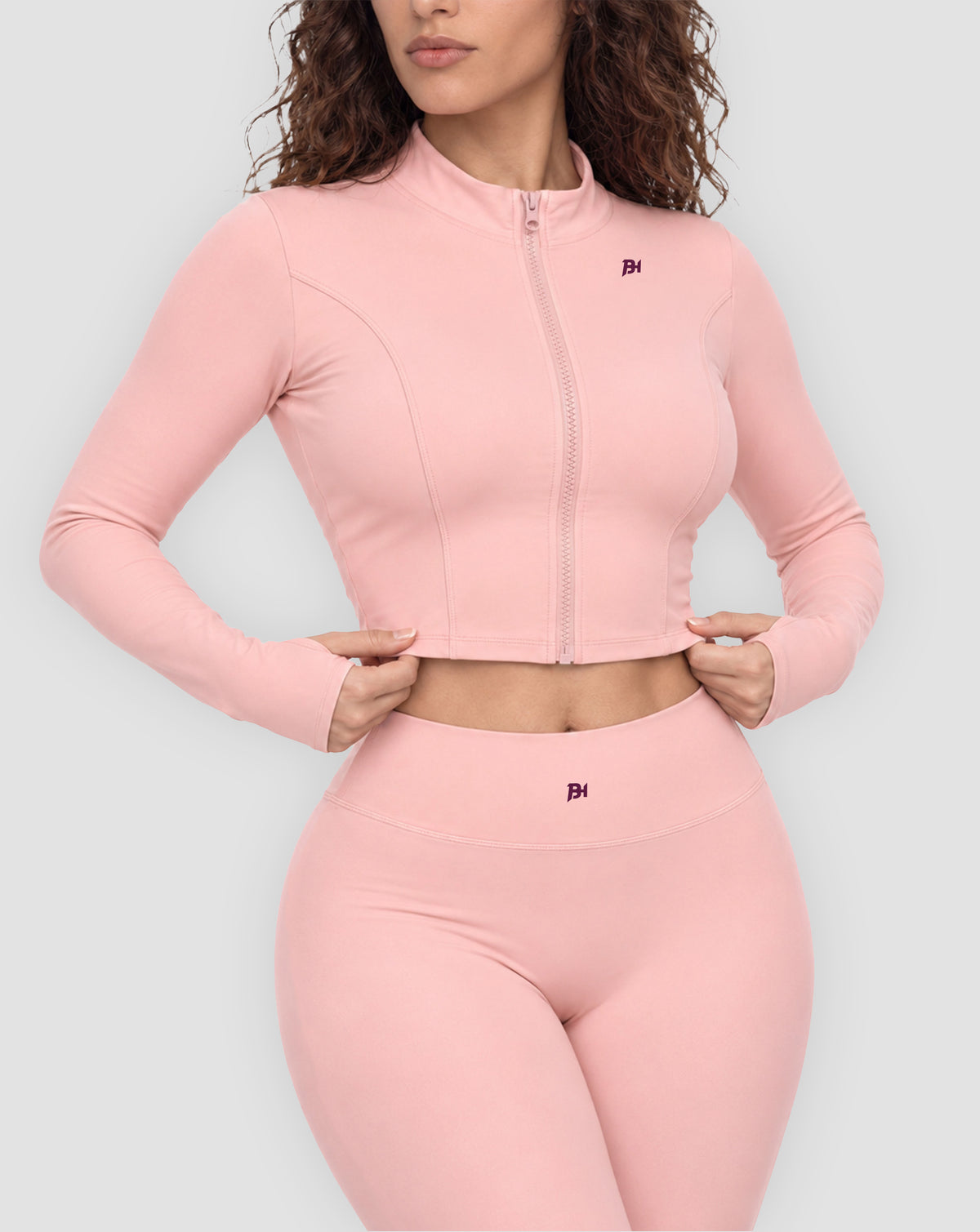 BEASTHAMMER Signature crop jacket in pink, worn front view with stand collar, full zip and BH monogram, styled with matching Signature scrunch leggings