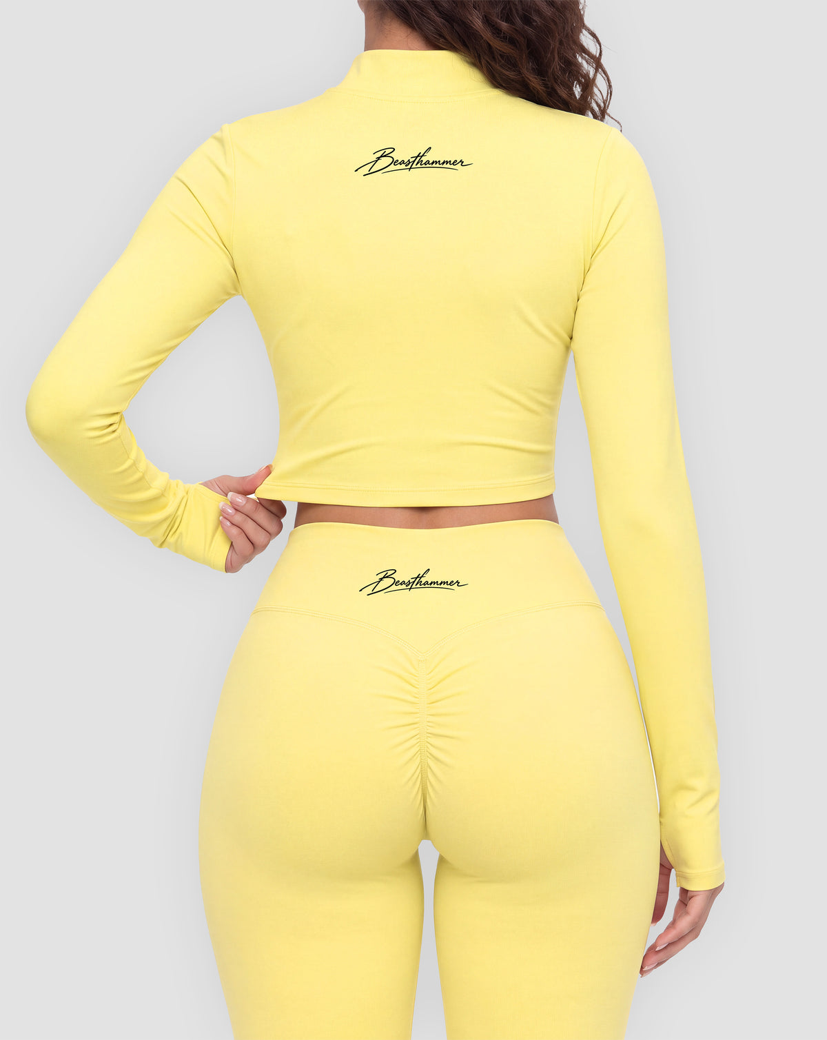 BEASTHAMMER Signature crop jacket in butter yellow, worn back view with the handwritten Beasthammer script logo across the upper back, styled with matching Signature scrunch leggings