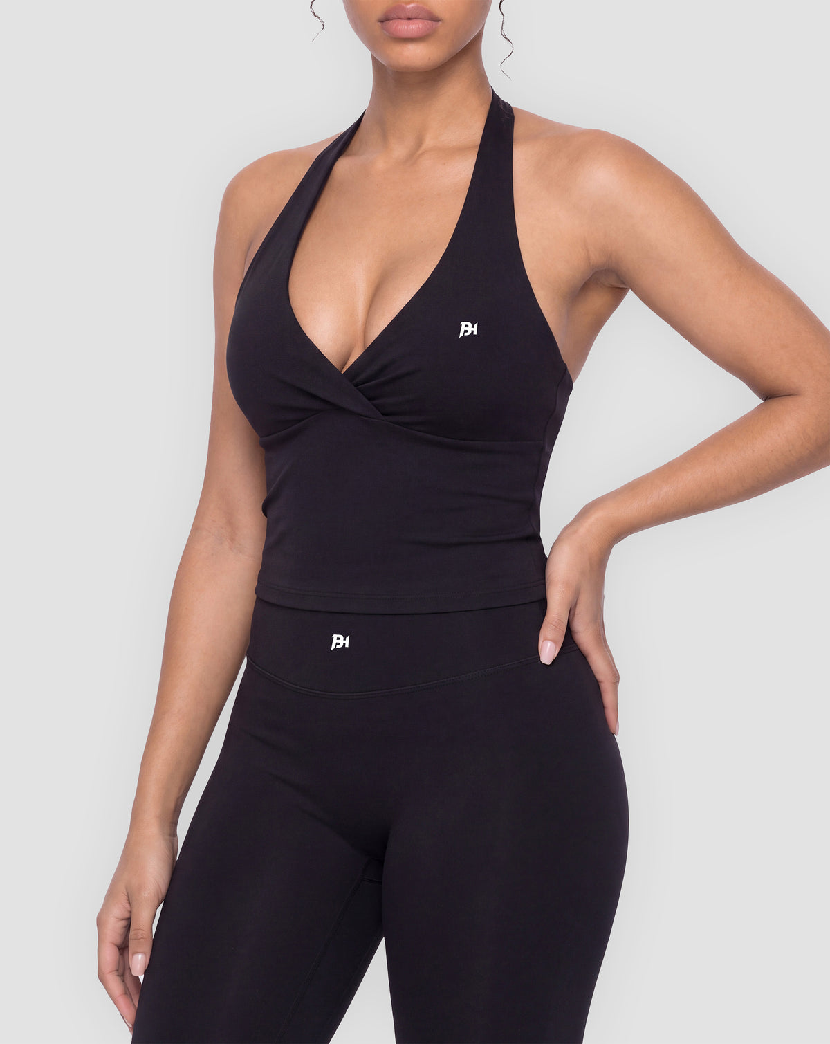 BEASTHAMMER Signature halter top in black, worn front view with halter neck and ruched twist, styled with matching Signature scrunch leggings