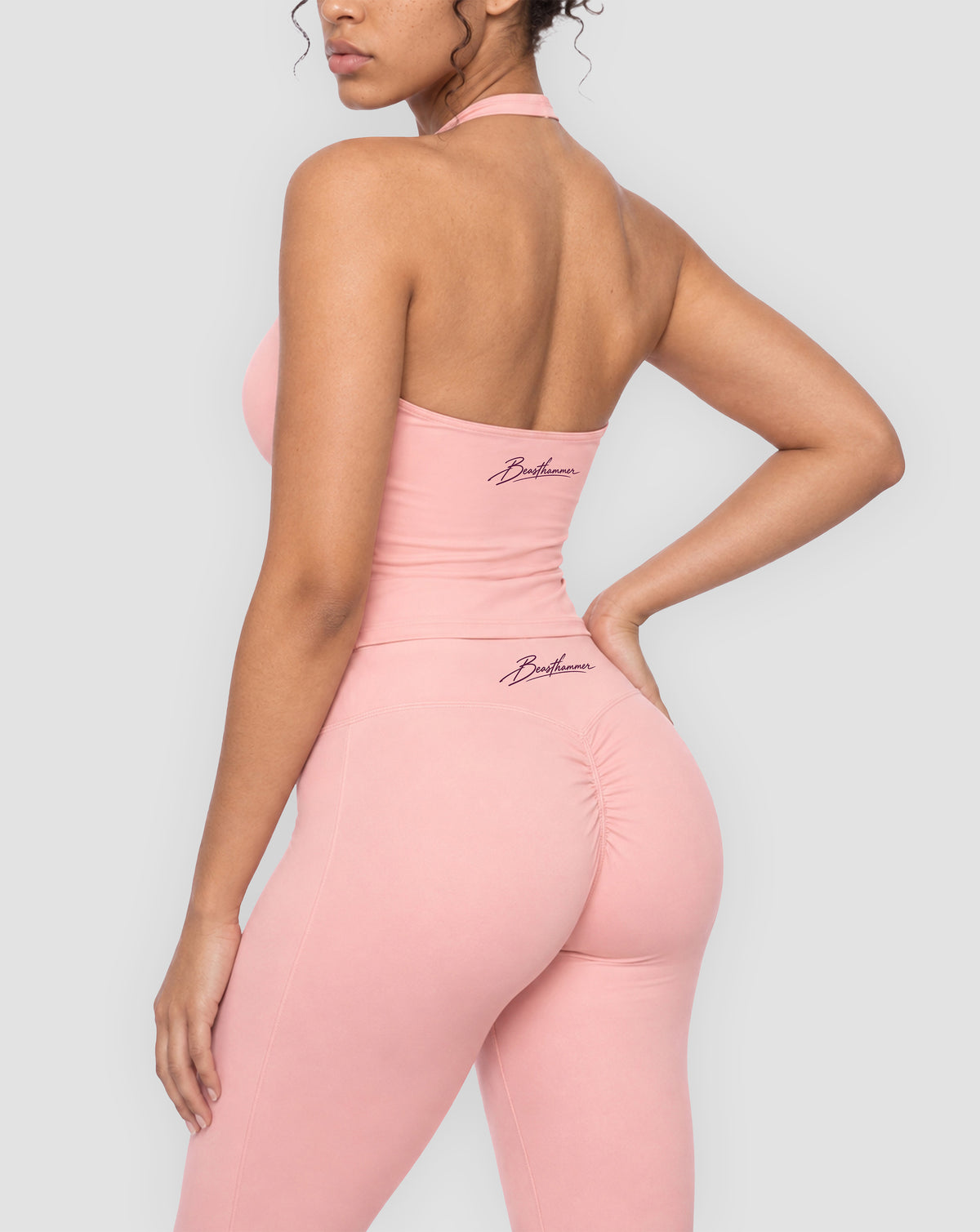 BEASTHAMMER Signature halter top in pink, worn back three-quarter view with the handwritten Beasthammer script logo